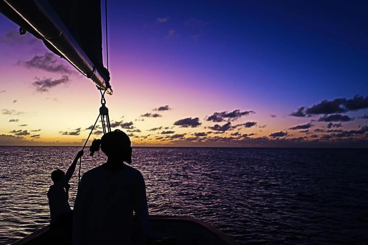 a man standing in front of a sunset over a body of water