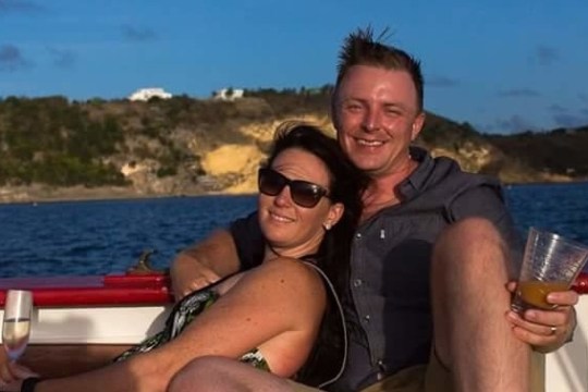 a person sitting in front of a body of water posing for the camera